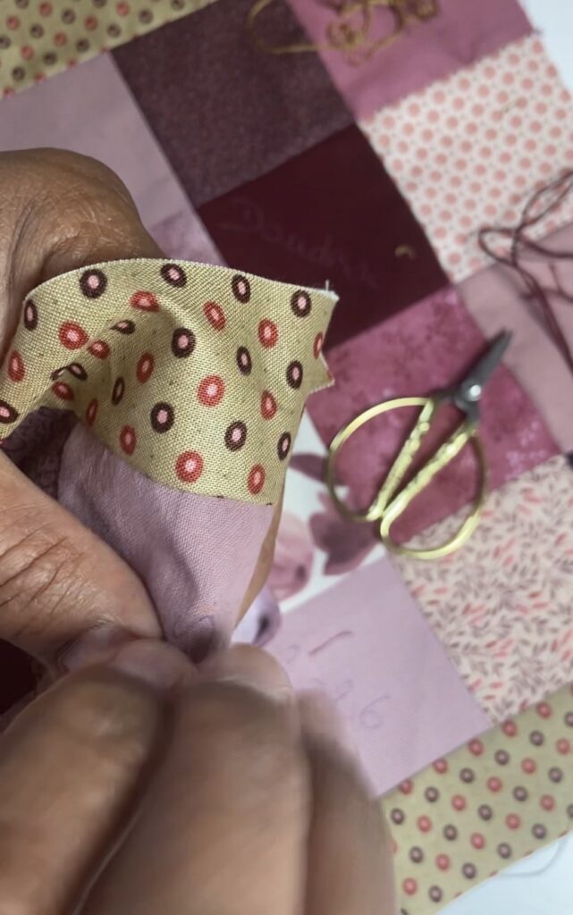 Couture main en patchwork avec petits carrés de tissu, aiguille et fil en cours d’assemblage