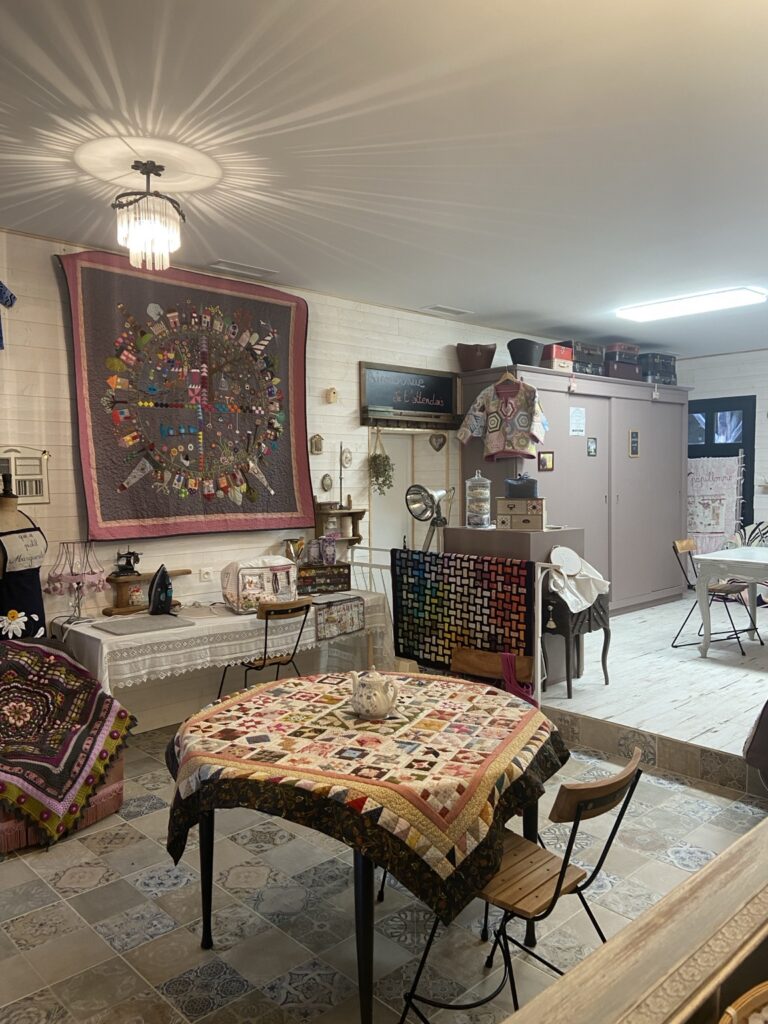 Atelier créatif M Papillonne en Dordogne avec tables de travail, ouvrages textiles, patchwork et matériel de broderie.