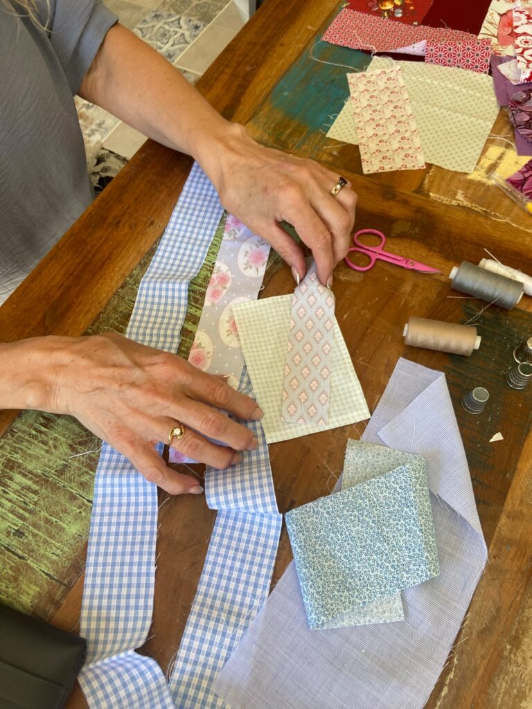 Mains disposant des morceaux de tissu pour composer un ouvrage de patchwork.